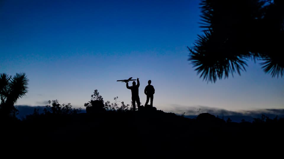 Mark Mitchell launching a model plane at dusk